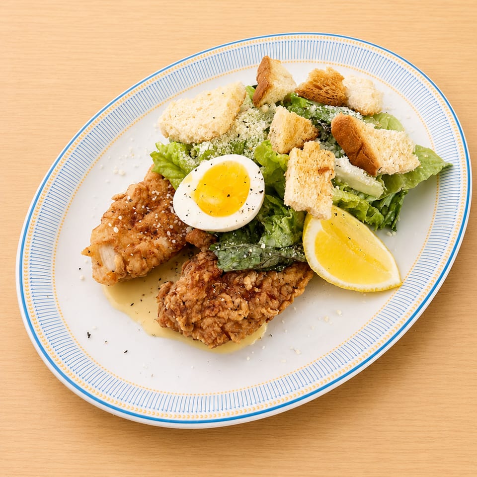 Fried chicken tenders with a side salad, croutons, parmesan, a boiled egg, and lemon wedge.